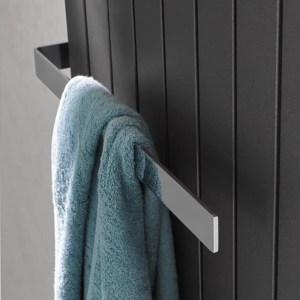 Ein Handtuchhalter aus glänzendem Metall hängt an einer dunklen Wand mit vertikalen Fugen. Ein hellblaues Handtuch ist daran gehängt, was dem Bild eine funktionale Note verleiht.