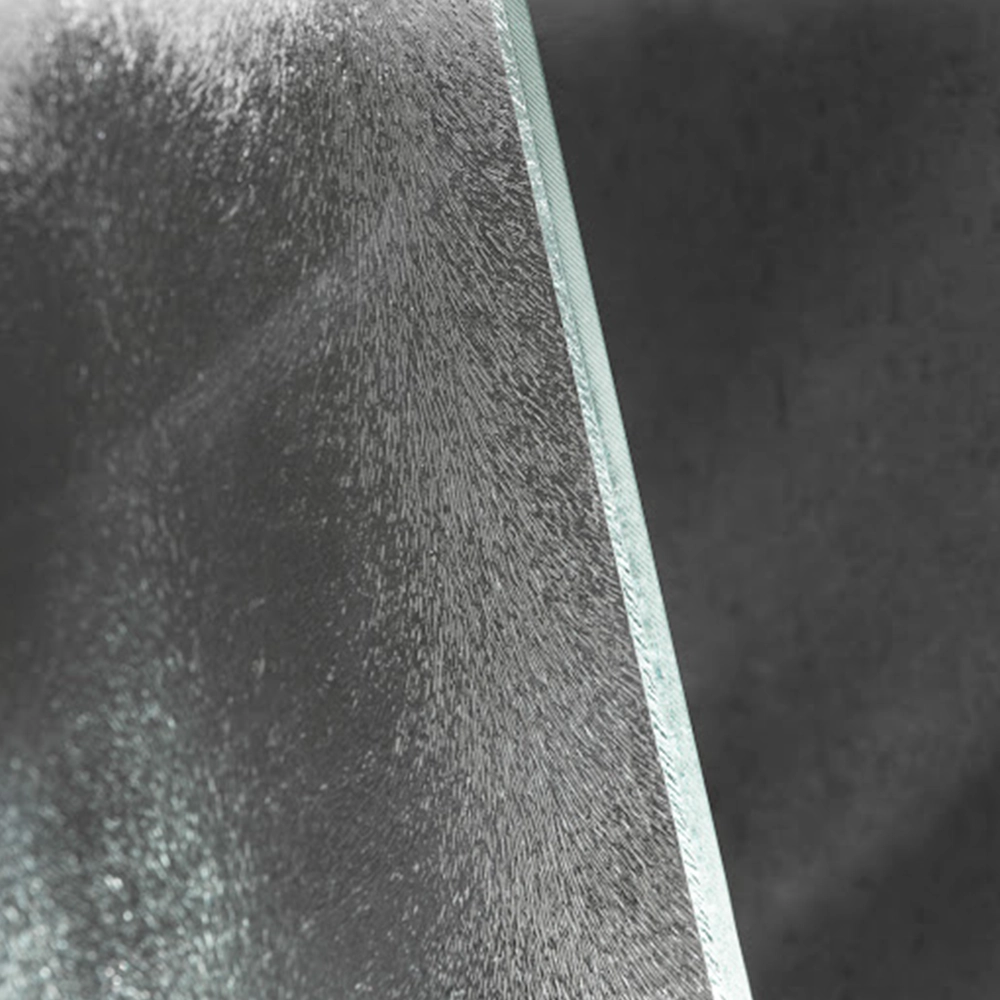 Eine gläserne Oberfläche mit einer strukturierten, matten Textur wird von einer schlichten, dunklen Hintergrundfläche umgeben. Die Kante des Glases ist klar und scharf, was einen modernen Eindruck vermittelt.